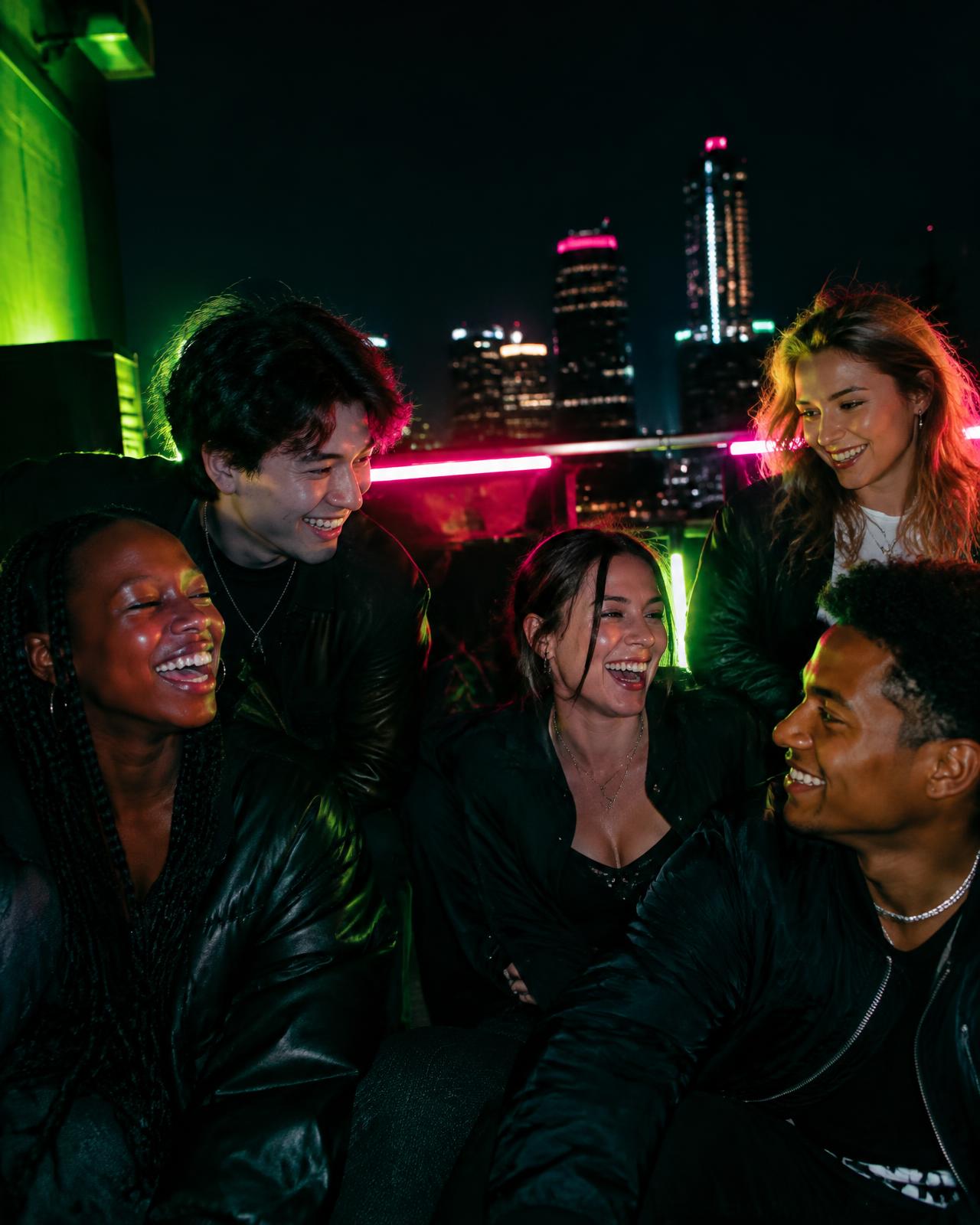 Friends laughing together on a rooftop at night